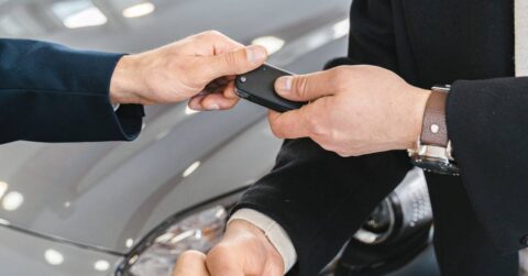A hand giving away the keys of a sold car.