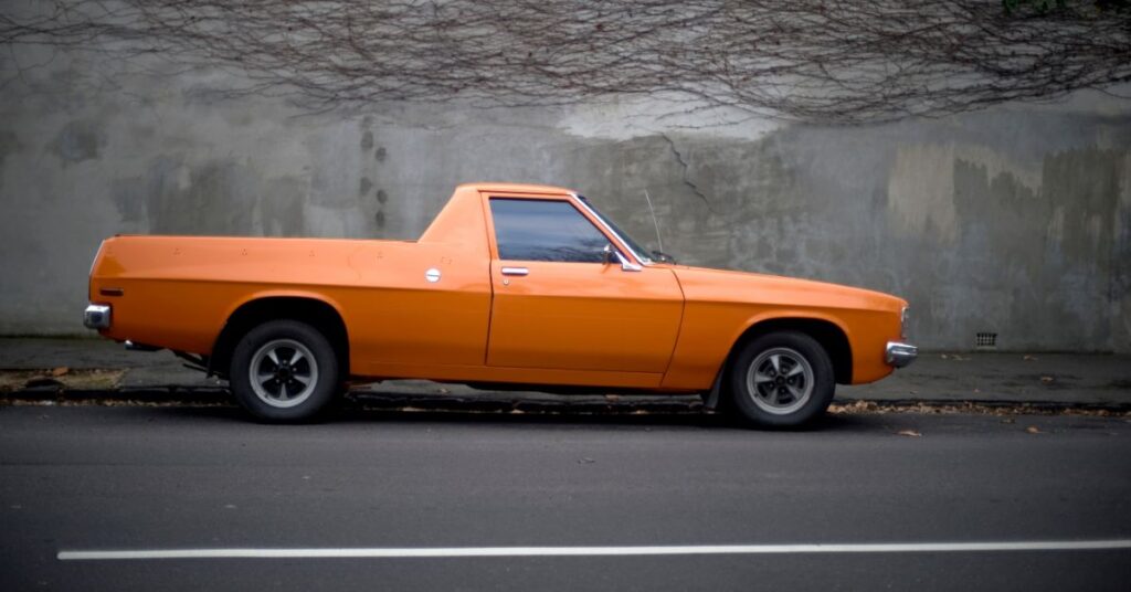 An orange Utility vehicle on a black road.