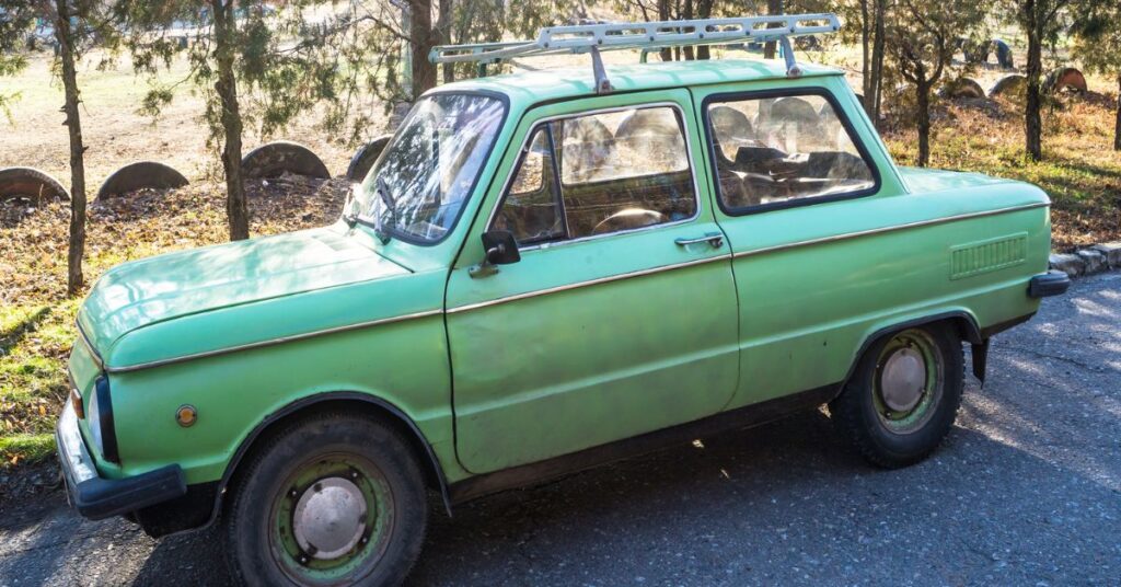 Old green car parked in a street.