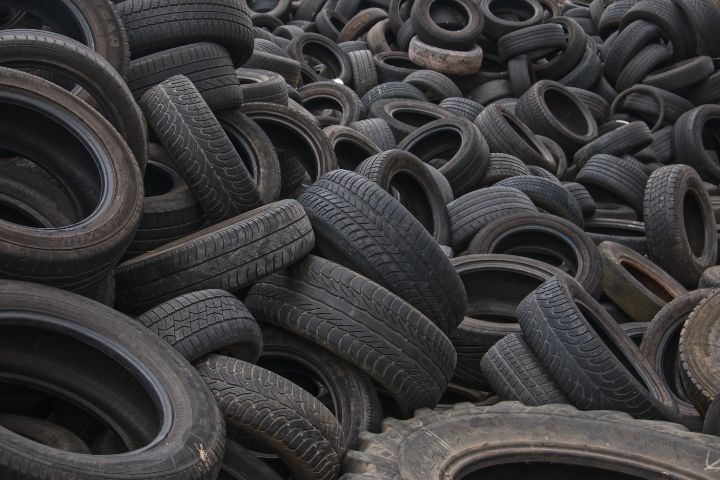 A large heap of discarded rubber tires is piled chaotically, forming a dense and sprawling mass of scrap.